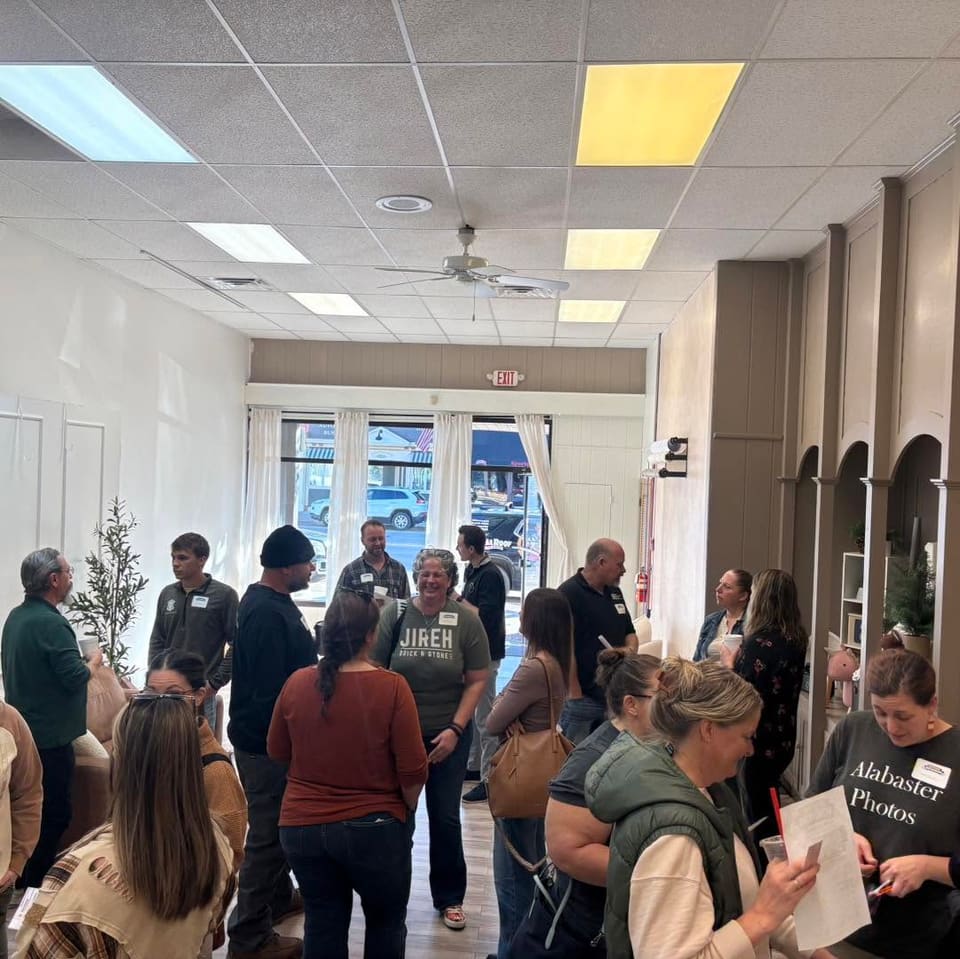 Members talking and laughing in a storefront space with tall windows