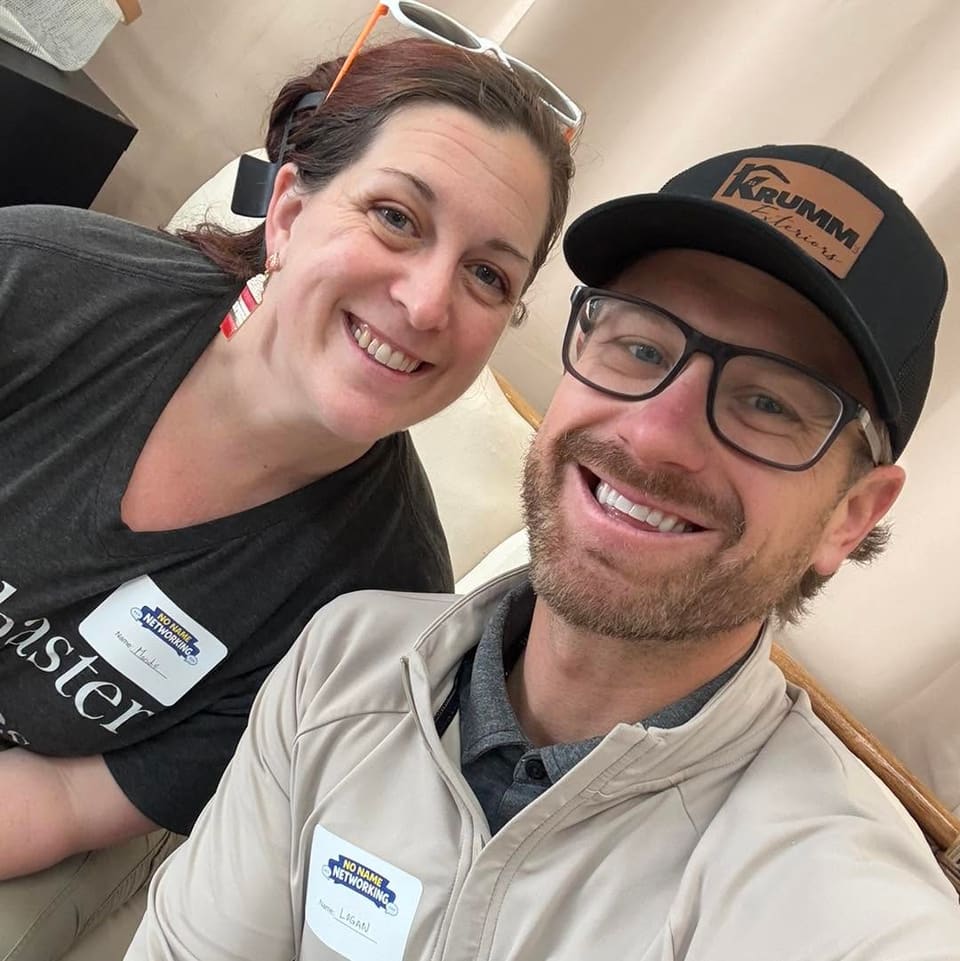 Two members smiling for a selfie, wearing No Name Networking name tags